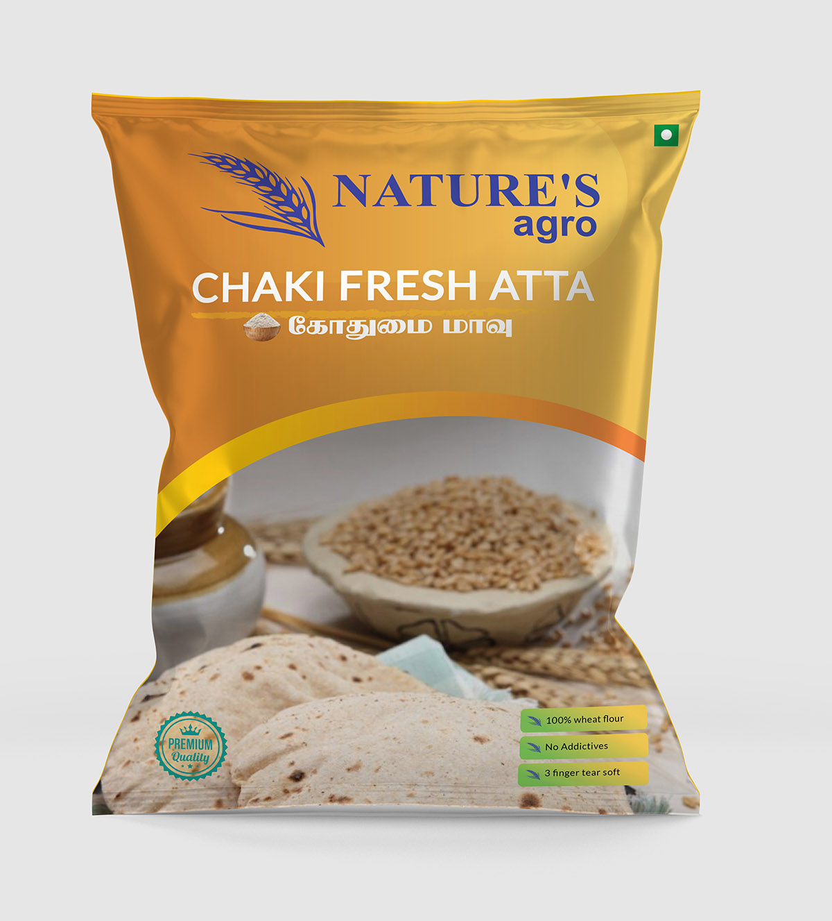 Packaging design for Nature's Agro Chakki Fresh Atta featuring a golden-yellow background with an image of wheat grains, a bowl of flour, and a stack of fresh rotis. The design includes text in English and Tamil, highlighting the product name and attributes, and a small Indian flag to indicate the product's origin.