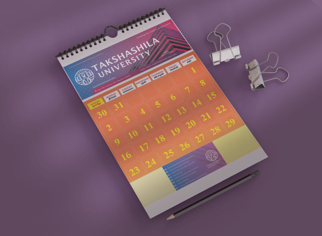 Vibrant monthly calendar mockup showcasing high-quality printing from the best printing service in Chennai. The calendar features bold, colorful dates and a professional design for Takshashila University, printed on a sturdy spiral-bound format. Accompanied by stationery items like binder clips and a pencil, the layout demonstrates precision and superior print quality, ideal for corporate or educational materials.